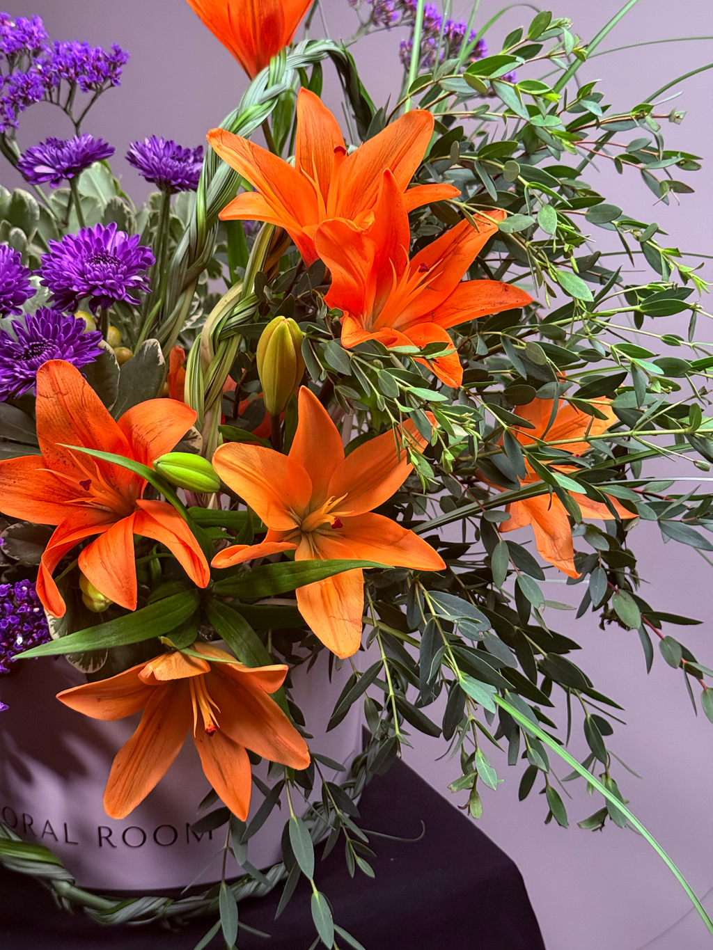 Close-up detail of Kinetic Line box arrangement showing purple pom mums and cascading date berries